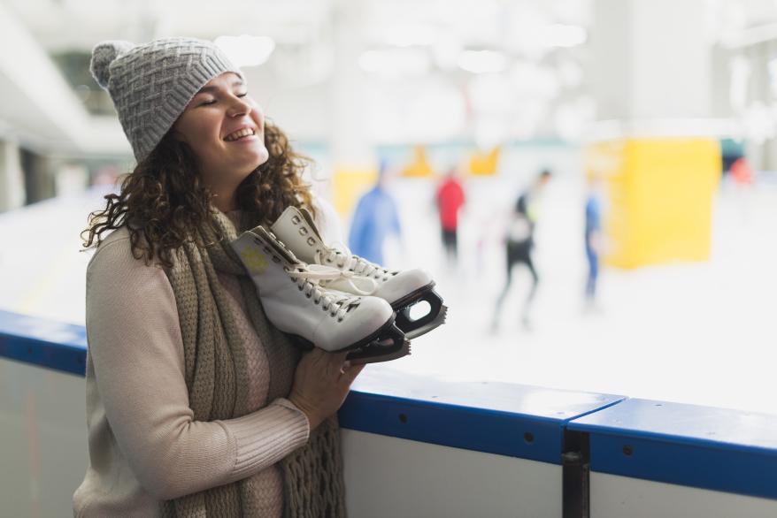 cheerful-woman-holding-ice-skates.jpg коньки
